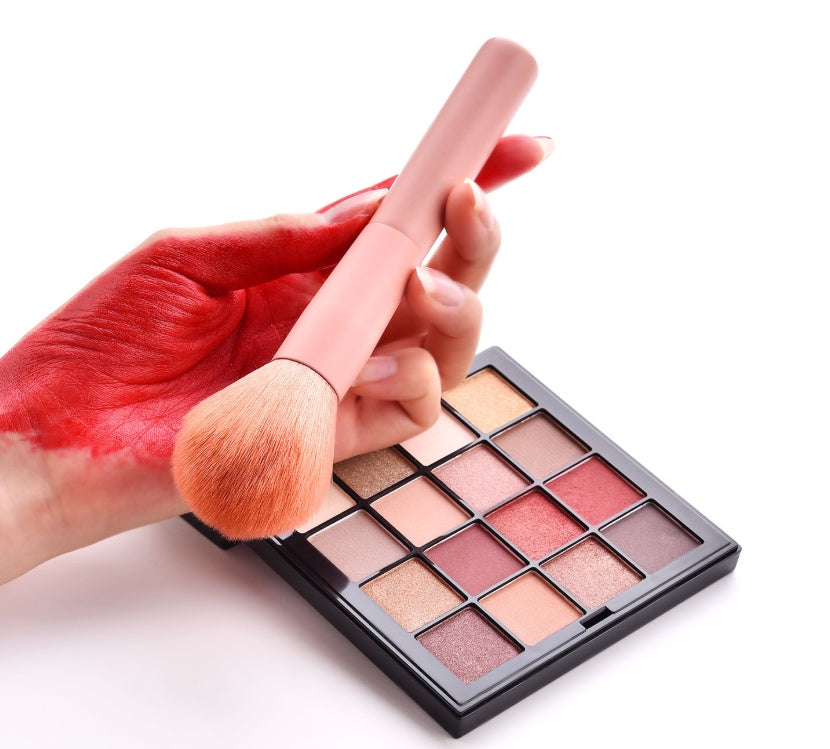 Makeup brush being used on a makeup palette with a white background