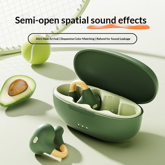 Ear Clip Bluetooth Wireless Headphones - Green earbud case with earbuds on a light surface with avocado and tennis ball in the background.