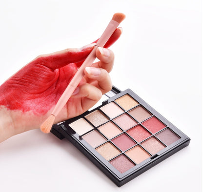 Makeup palette with a brush and a hand holding it on a white background