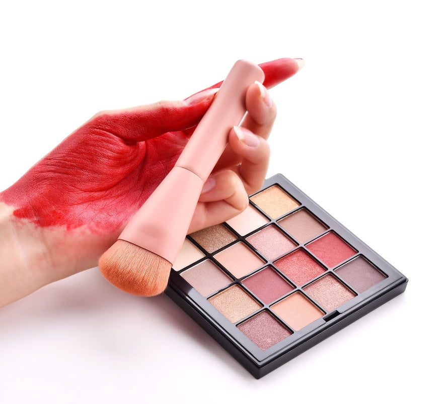 Makeup brush and palette with red hand on a white background