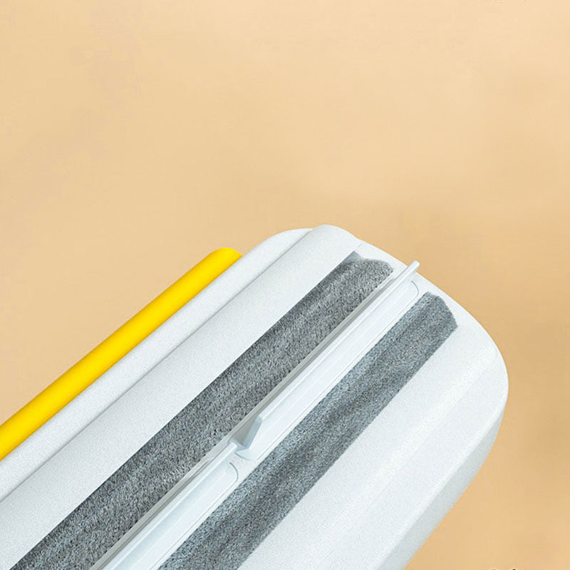 Cleaning tool with a white base, gray scrubber, and yellow handle on a beige background