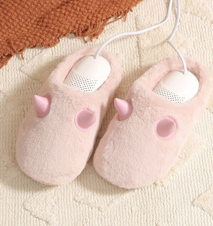 Pair of pink slippers with unicorn design on a textured surface