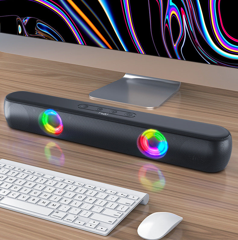 Black soundbar with colorful lights on a desk with a computer monitor, keyboard, and mouse.