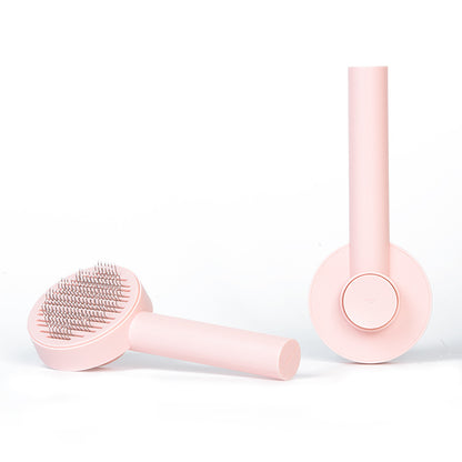Pink grooming brush and round brush head on a white background