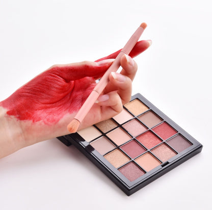 Makeup palette with a brush and hand with red lipstick on a white background