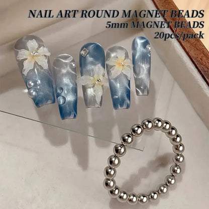 Nail art round magnet beads with floral design on nails and a bracelet on a light background.