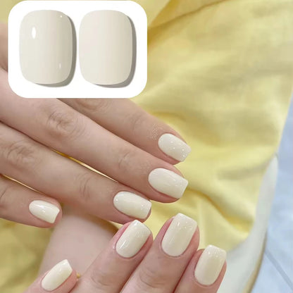 Close-up of hands with beige nail polish on a yellow fabric background