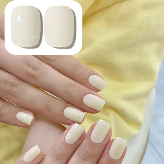 Close-up of hands with beige nail polish on a yellow fabric background