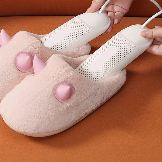 Pink heated slippers with a white heating element being plugged in on an orange surface.