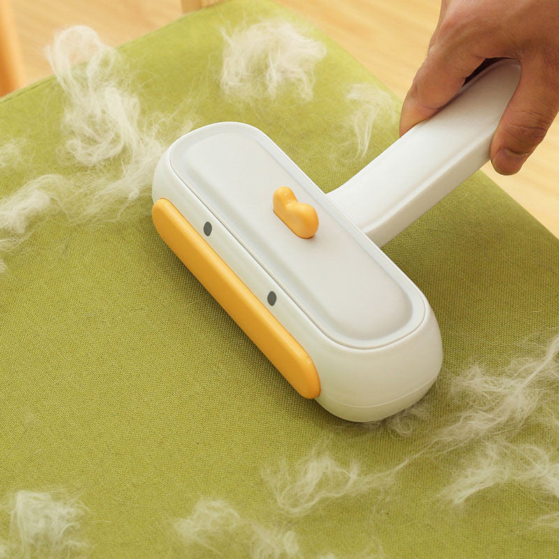 Pet hair remover with white and yellow design on a green surface with pet hair.