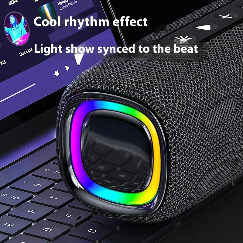 Black portable speaker with rainbow light effects on a laptop