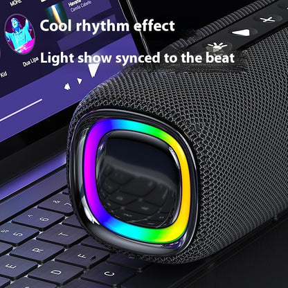 Black portable speaker with rainbow light effects on a laptop