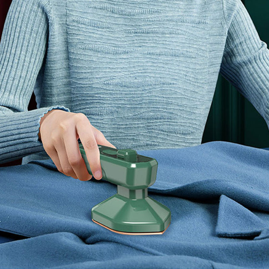 Person ironing fabric with a green iron on a blue surface
