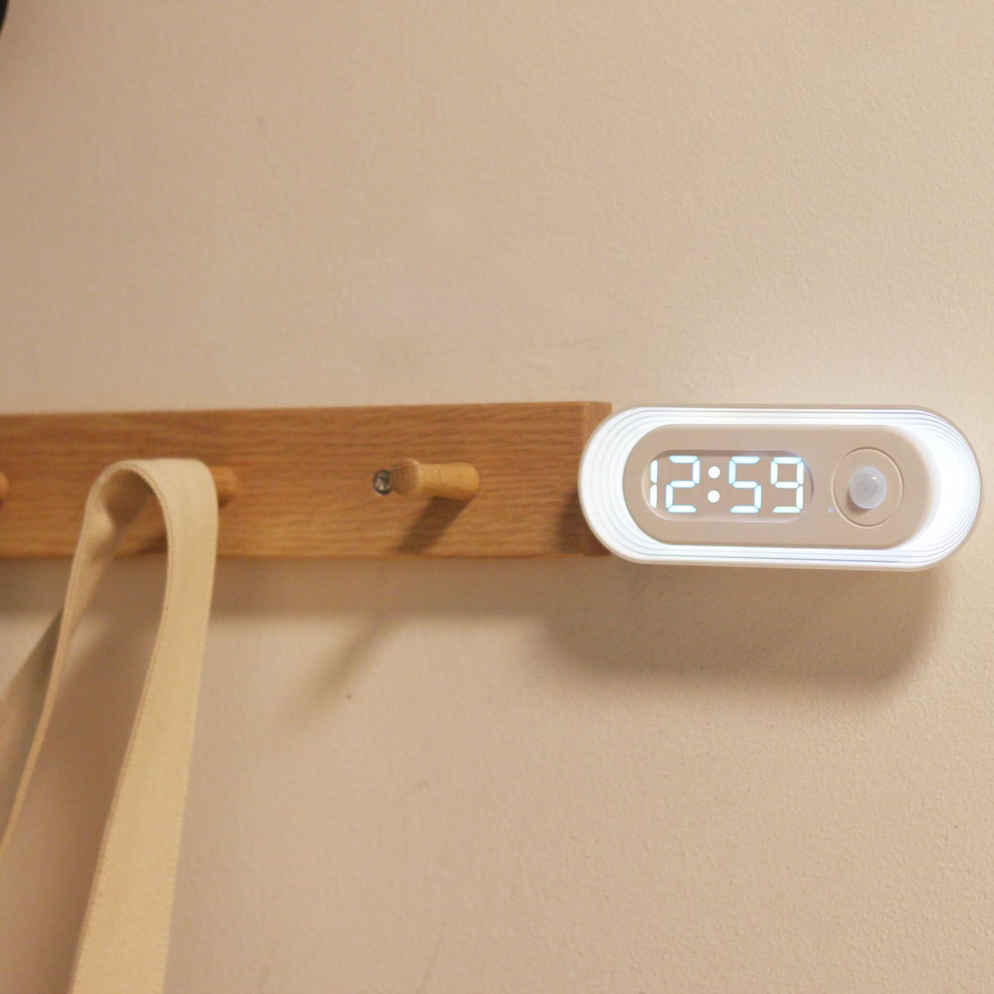 Wooden wall hook with digital clock displaying 12:59 on a beige background