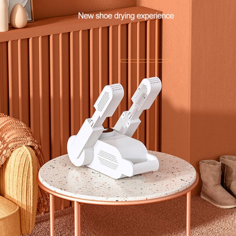 White shoe dryer on a round table with brown boots nearby, against an orange wall.
