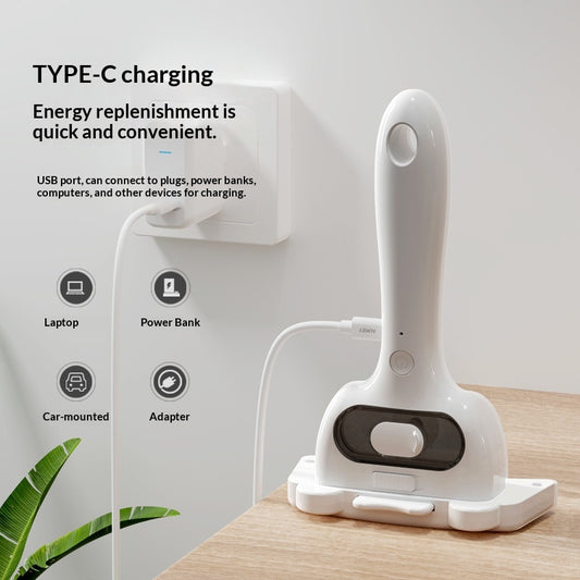 White handheld device with USB cable on a wooden surface, charging station in the background.